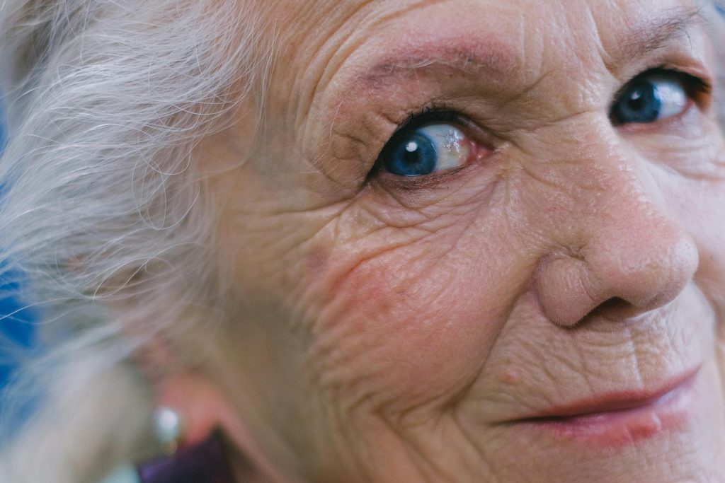 Idős hölgy mosolyog kék szemekkel